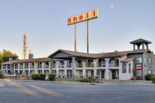 Un motel con un letrero de Shell, una torre de campanas y un anuncio del 'Crossroads Inn'.