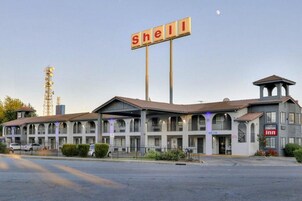 Un motel con un letrero de Shell, una torre de campanas y un anuncio del 'Crossroads Inn'.