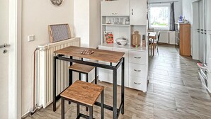 Een moderne keuken met een centraal eiland, witte kasten en uitzicht op de eethoek.