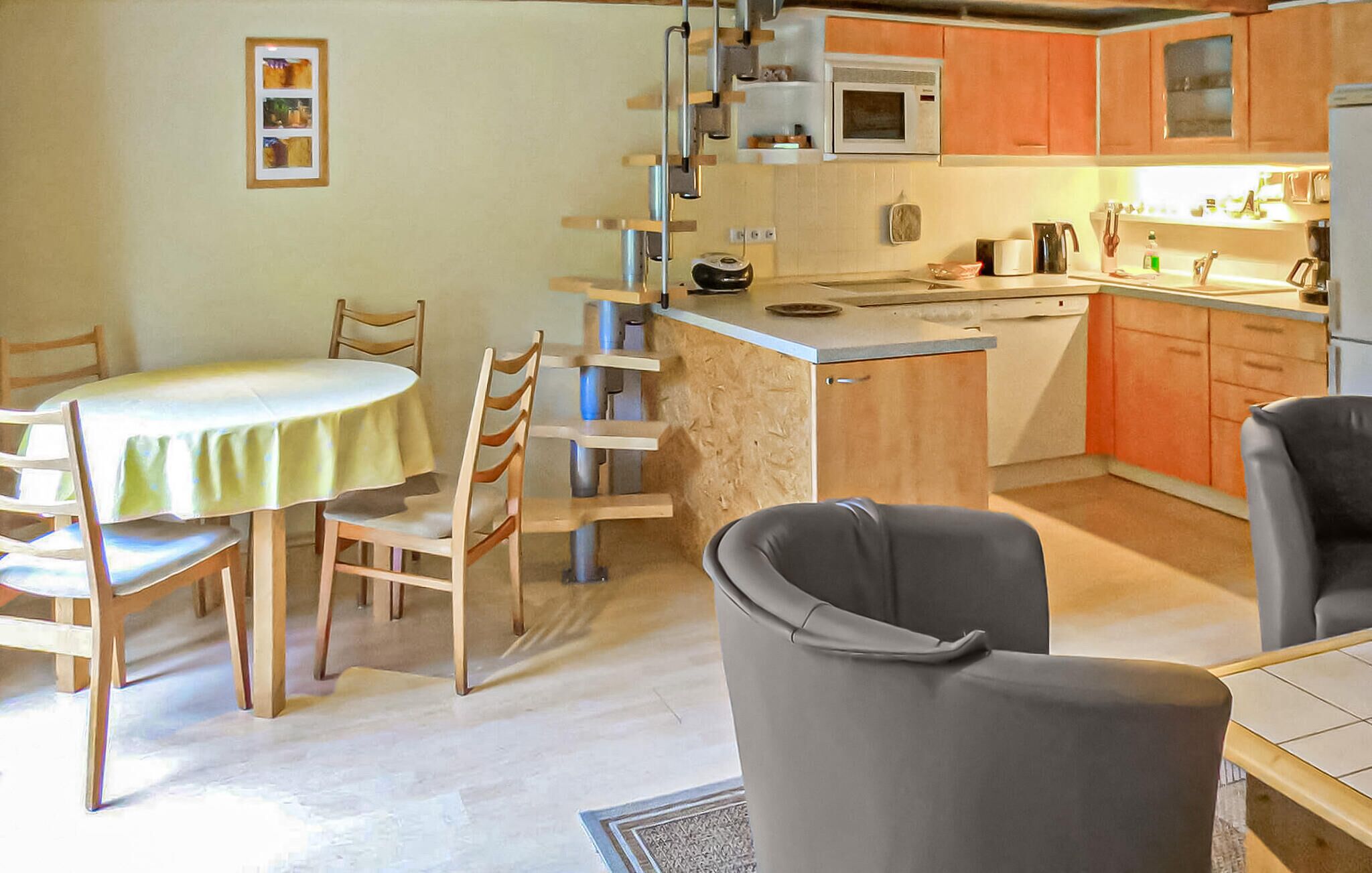 A compact kitchen with a dining area, featuring a table, chairs, and basic appliances.