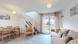 A modern interior with a dining area, a sofa, a staircase, and a view of the outside. - 39 Strawberry Hill, Tolroy Manor (Hayle)