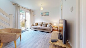 A living room with a sofa, a chair, a TV, and a small table with a remote. - 39 Strawberry Hill, Tolroy Manor (Hayle)