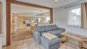 Ein modernes Wohnzimmer mit einem grauen Sofa, einem kleinen Tisch und einer Küche im Hintergrund.