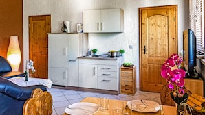 A compact living space with a kitchenette, a dining area, and a seating area with a sofa and a table set for two.