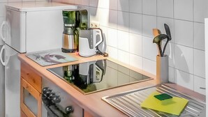 Een keuken met een koffiezetapparaat, waterkoker en keukengerei op het aanrecht.