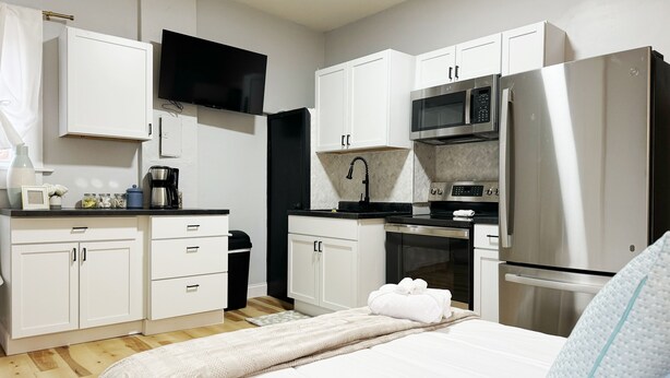 A compact hotel room with a kitchenette, a bed, and a television.