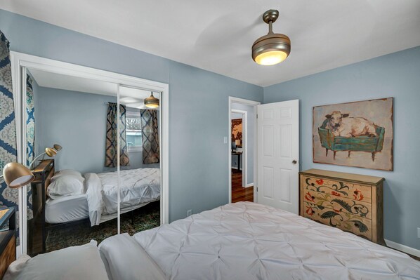 A bedroom with a bed, a dresser, a mirror, and a ceiling fan.