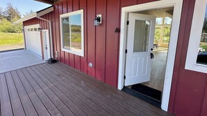 En röd byggnad med en överbyggd veranda, ett garage och en dörr som leder till ett skyddat område.