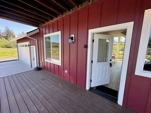 A red building with a covered porch, a garage, and a door leading to a covered area. - Gorgeous cabin, secluded fishing pond, swimming, paddling. Central for Daytrips! (Elma)