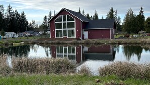 En rustik byggnad med stora fönster och en spegelbild i en damm.