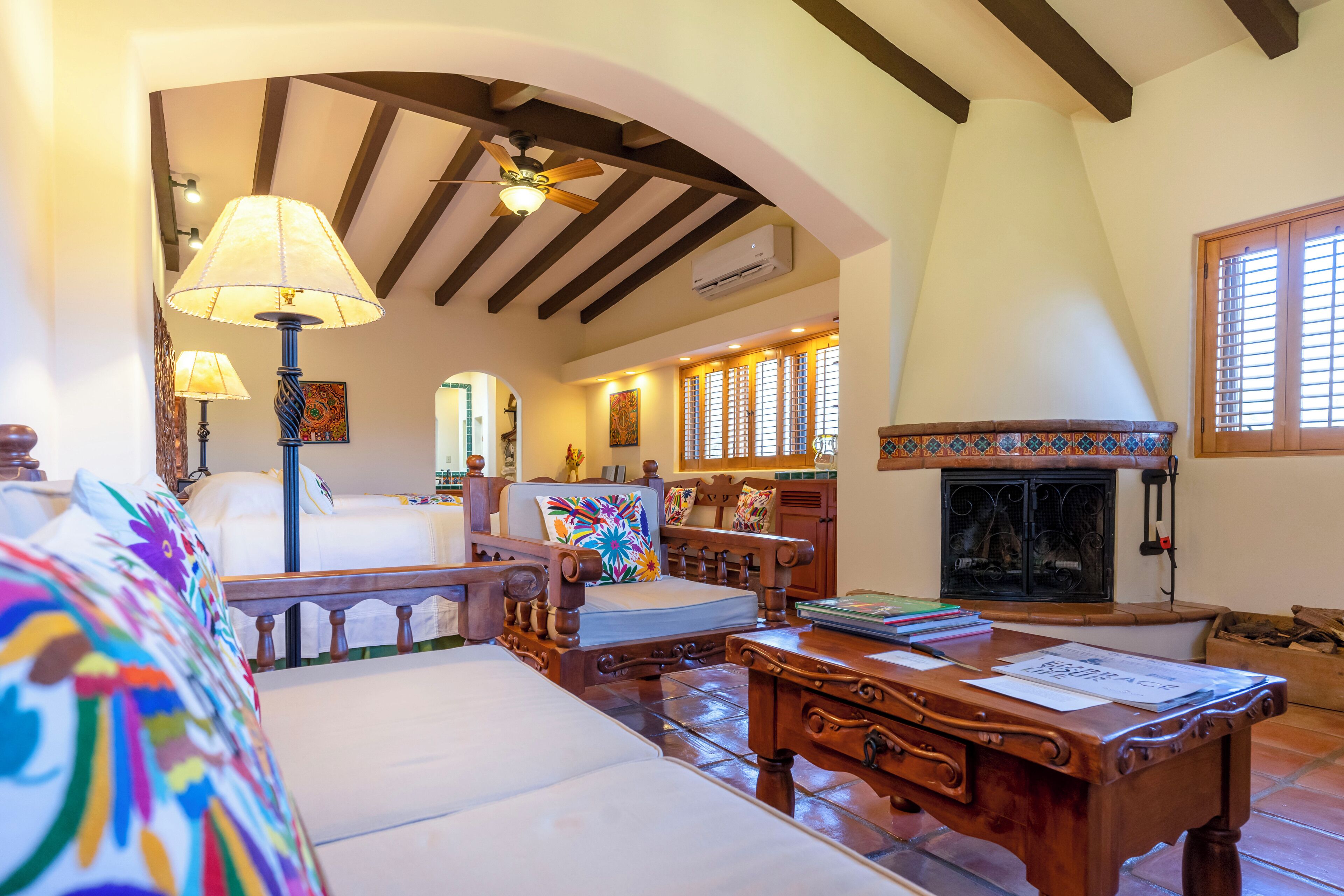 A cozy living room with a fireplace, wooden furniture, and a ceiling fan.