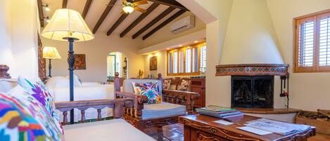 A cozy living room with a fireplace, wooden furniture, and a ceiling fan.