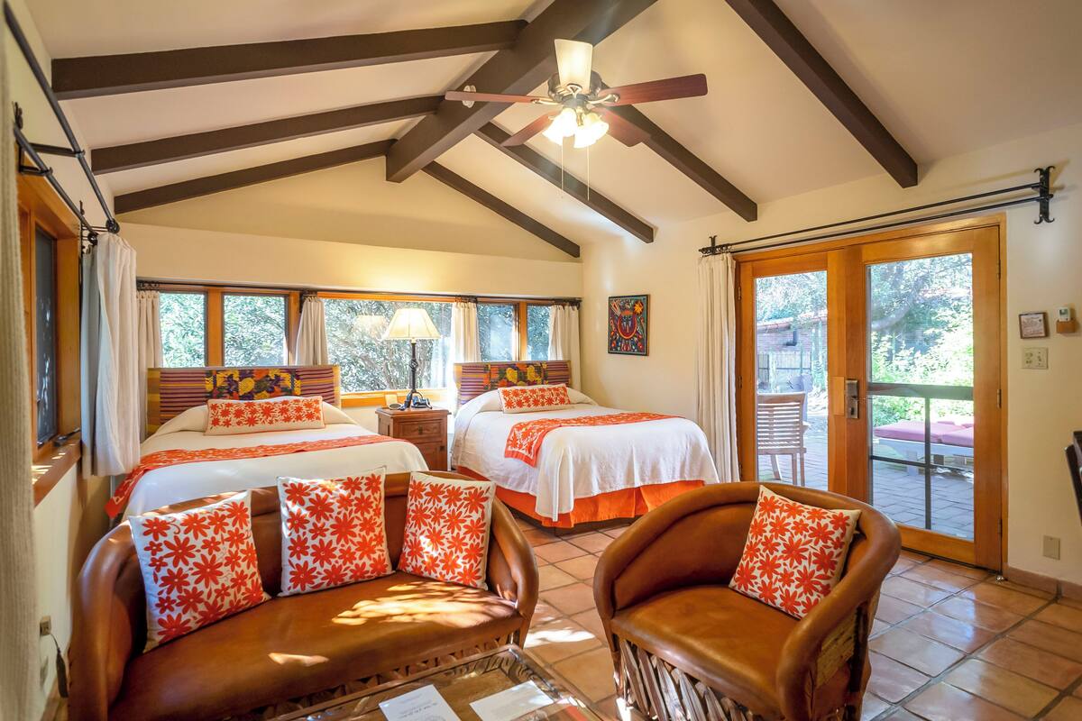 A bedroom with two beds, a ceiling fan, and a view of the outdoors.