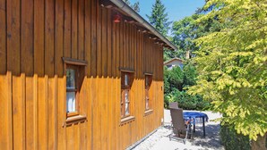 A wooden building with multiple windows and a covered outdoor seating area.
