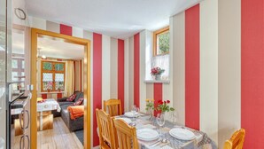 A dining area with striped walls, a table set for two, and a window with a view.