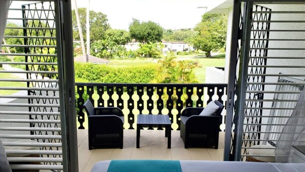 Een balkon met een bed, twee stoelen en een tafel.