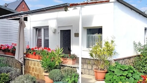 A white house with a small garden, potted plants, and a wooden fence. - Ferienhaus Waren (Müritz) (Waren (Müritz))