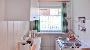 A compact kitchen with a window, a stove, and a sink. - Ferienhaus Waren (Müritz) (Waren (Müritz))