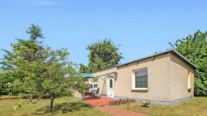 Ein kleines, eingeschossiges Gebäude mit Terrasse, einer Tür und einem Fenster.