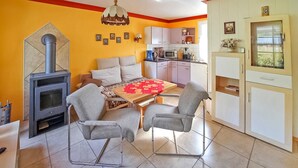 Un accogliente soggiorno con camino, un tavolo da pranzo con sedie e un angolo cottura con pensili ed elettrodomestici.