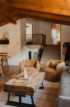 Cozy living space with a rustic aesthetic, featuring a coffee table, armchairs, and a sofa.
