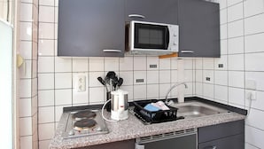 A compact kitchen with a microwave, stove, and sink.