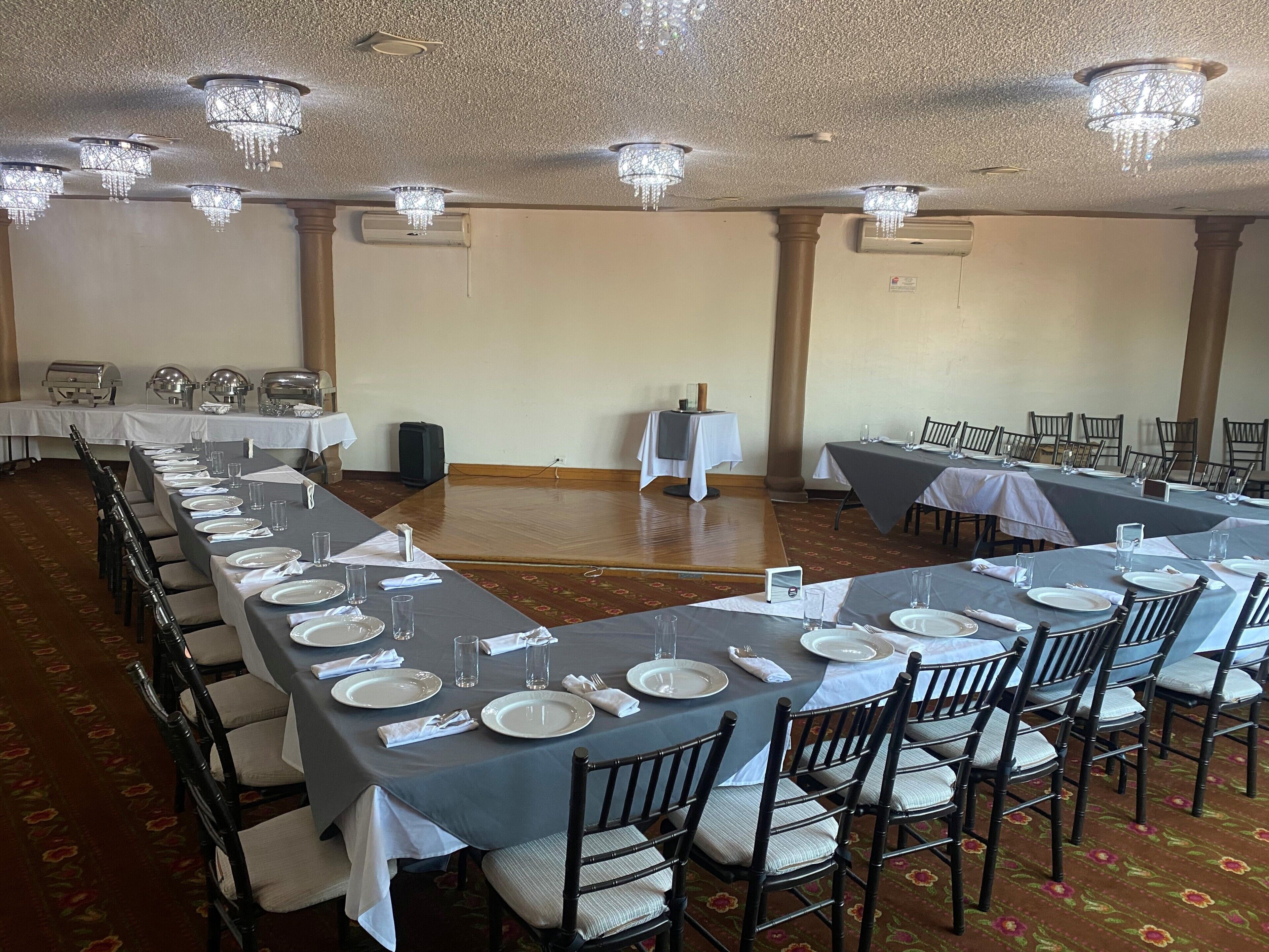 A conference room with long tables set for a formal event, equipped with chairs, tables, and a speaker system.