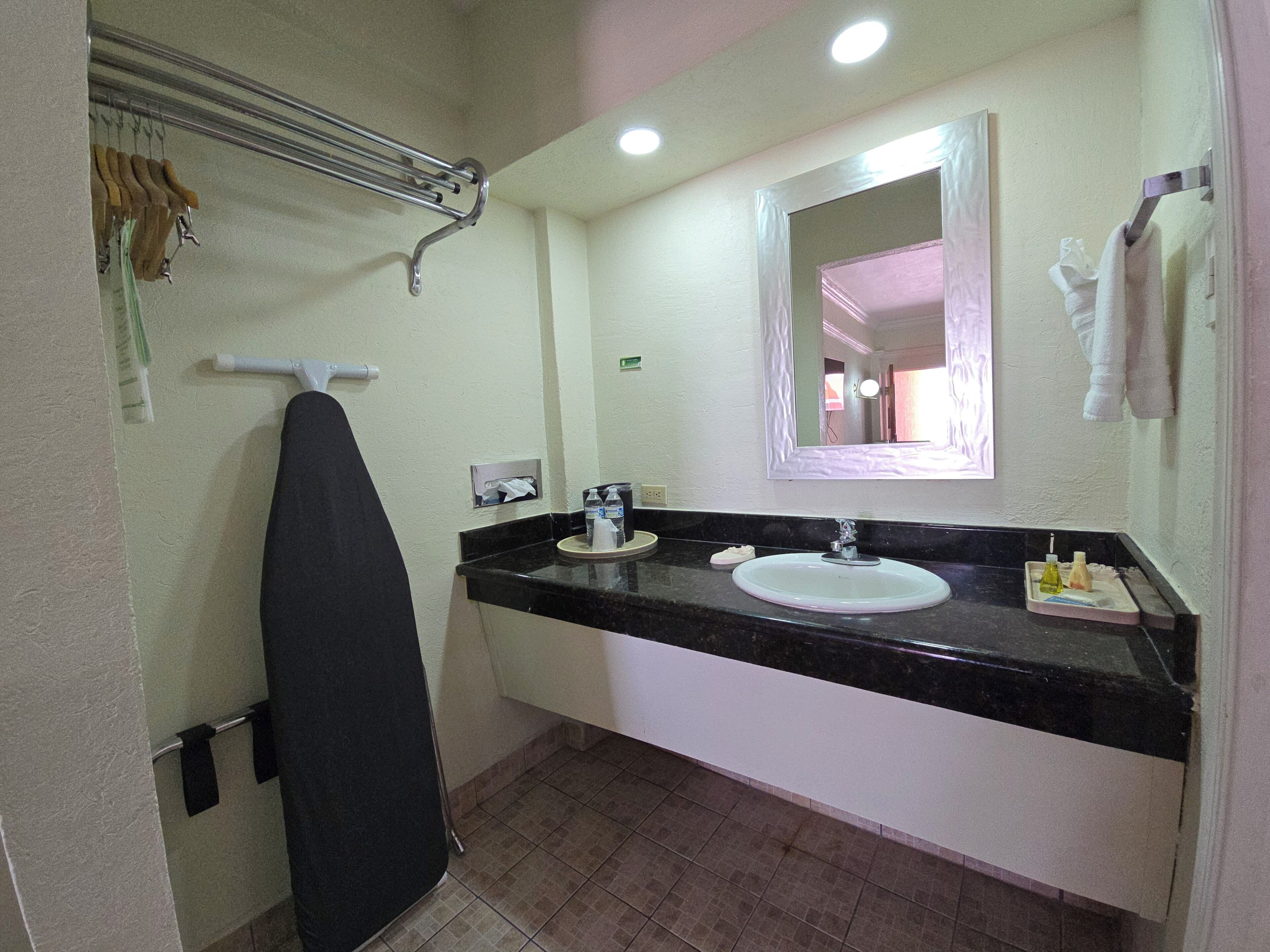 Un baño con encimera negra, lavabo blanco y espejo sobre el lavabo.