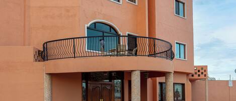 A hotel with a prominent sign, a balcony with seating, and a large entrance door.