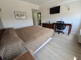 Habitación de hotel con cama, escritorio, silla y televisor de pantalla plana montado en la pared.
