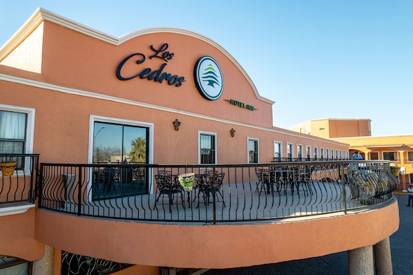 Un hotel llamado 'Los Cedros' con un balcón curvo distintivo y una zona de estar al aire libre.
