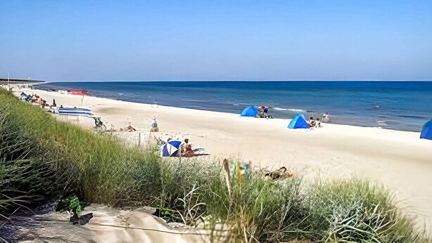 Ein Strand mit Zelten und einigen Personen.