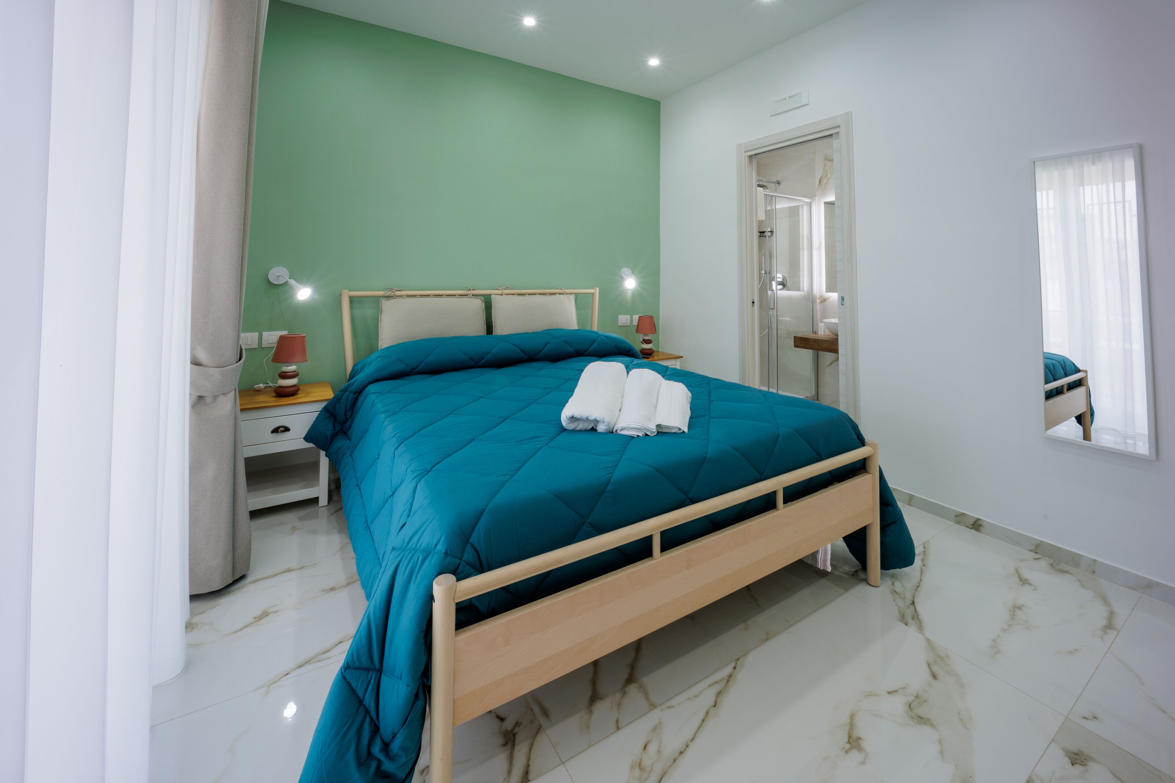 Ein Schlafzimmer mit Bett, Nachttischen, einem Spiegel und einer Tür.