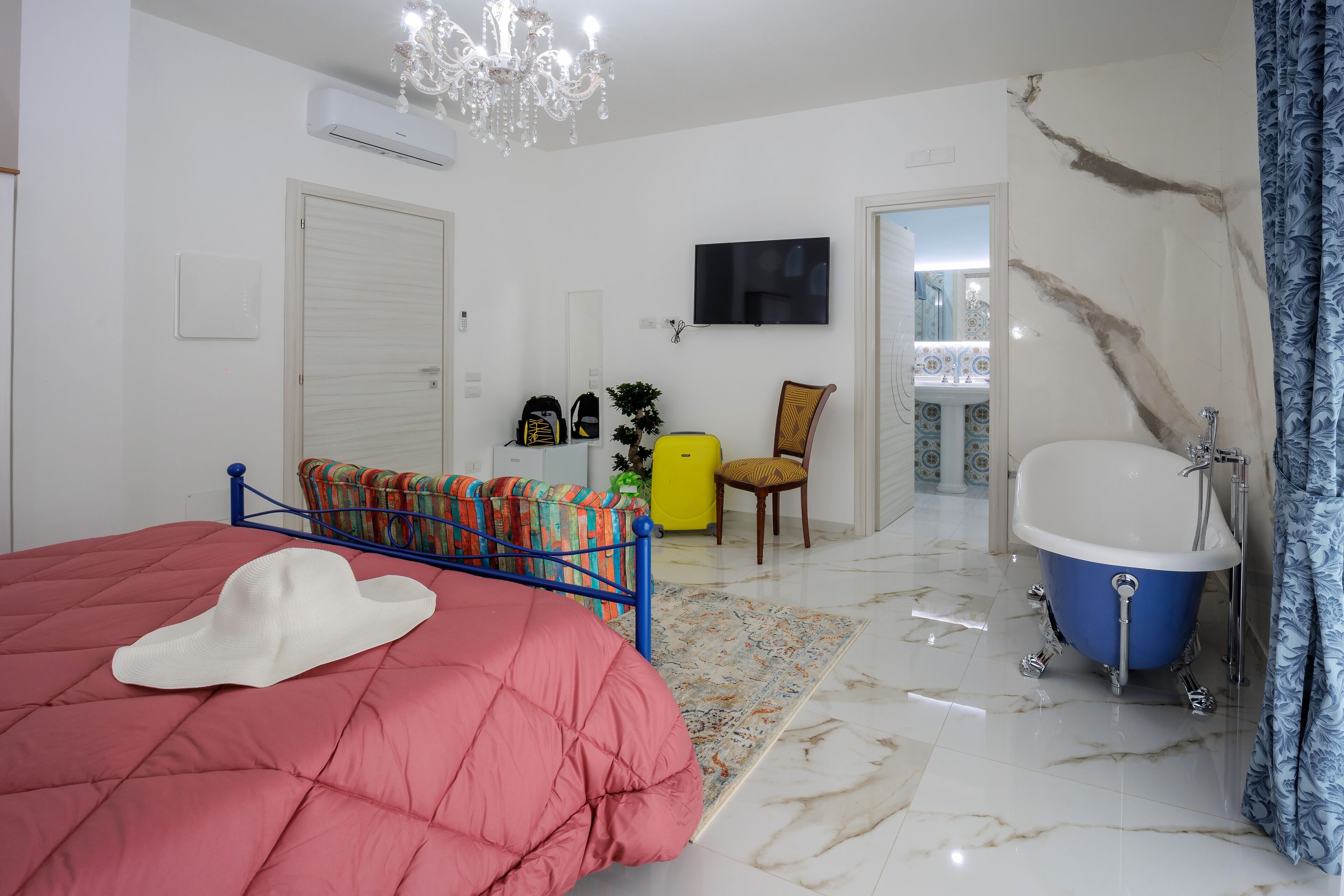 Un dormitorio con cama, televisión, baño con bañera y balcón con vistas.