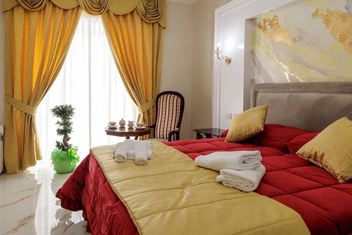 A hotel room with a large bed, a small table with a plant, and a chair.