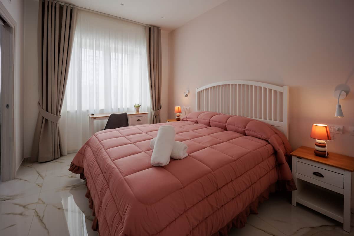 A bedroom with a large bed, a desk, and a chair.