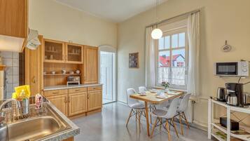 Eine moderne Küche mit Holzausstattung, einer Granit-Arbeitsplatte, einer Essecke mit Tisch und Stühlen sowie Blick auf Häuser durch ein Fenster.