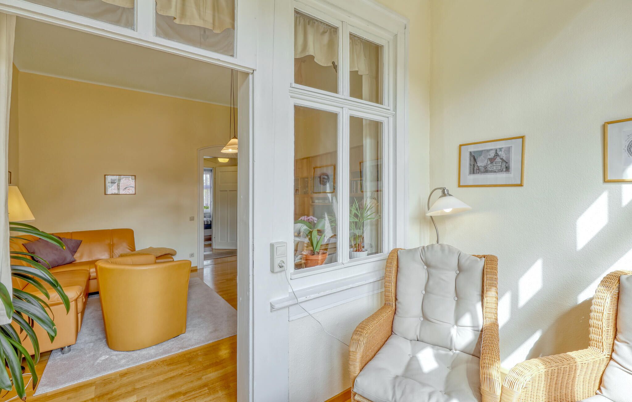 A room with a sofa, a chair, a lamp, and a window with curtains.