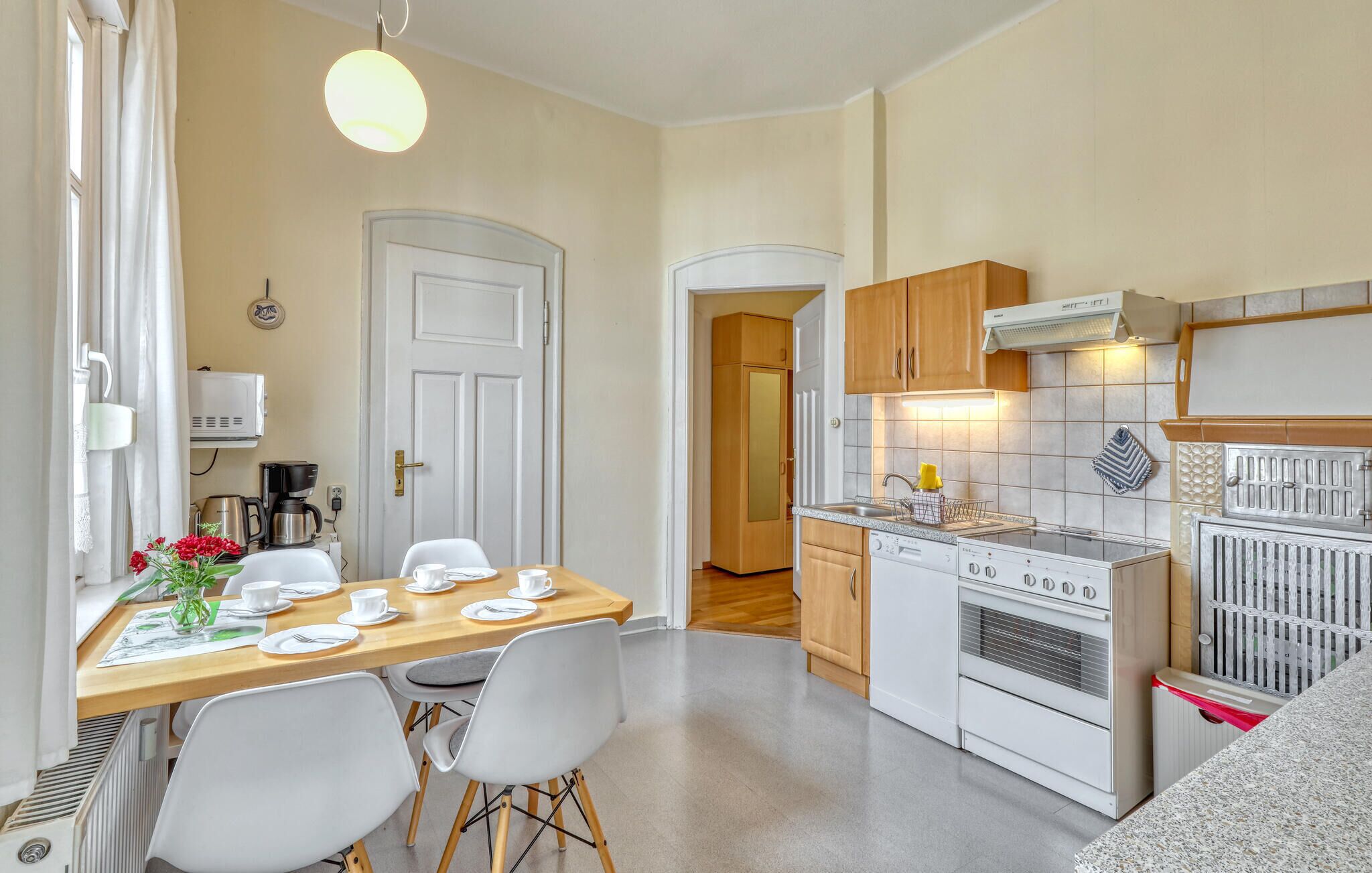 Une cuisine compacte avec un coin repas, des appareils électroménagers blancs et une petite table à manger pour quatre personnes.