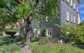 A building with a stone facade, multiple windows, and a garden with various plants and flowers. - Ferienwohnung Friedrichroda (Friedrichroda)