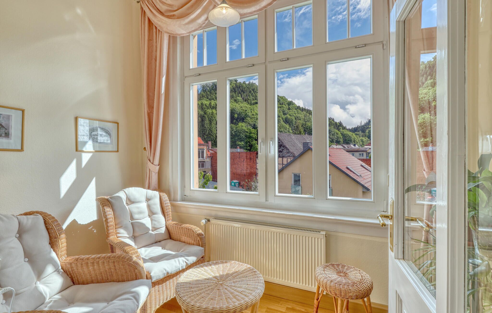 Ein Zimmer mit großem Fenster, Korbmöbeln und einer Heizung.
