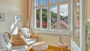A room with a large window, wicker furniture, and a radiator. - Ferienwohnung Friedrichroda (Friedrichroda)