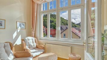 Ein Zimmer mit großem Fenster, Korbmöbeln und einer Heizung.