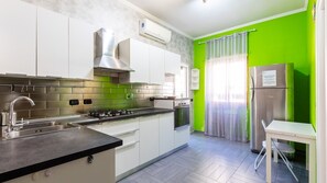 Una cucina moderna con mobili bianchi, un frigorifero in acciaio inossidabile e un fornello a gas.