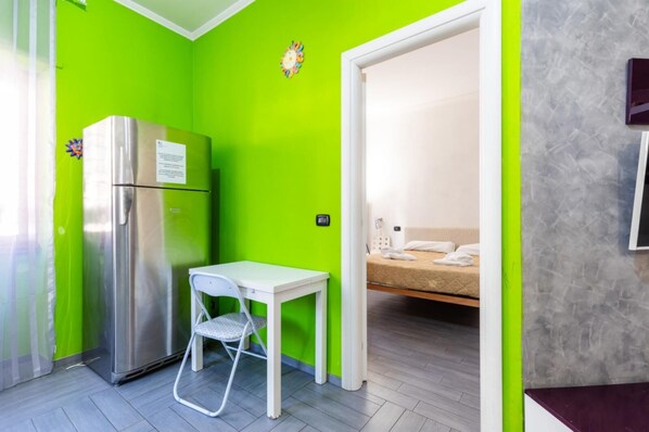 Une pièce compacte comprenant un coin cuisine, une petite table avec une chaise et un lit.