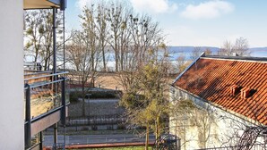 Ein modernes Gebäude mit einem Metallbalkon mit Blick auf einen Park mit Bäumen und einem See.