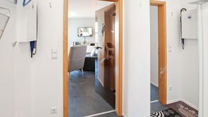 Ein Flur, der in einen Wohnbereich mit Fernseher, einer Couch und einem Couchtisch führt.