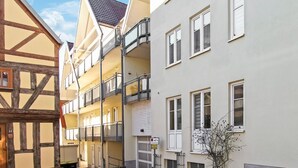 Eine schmale Straße mit traditionellen Fachwerkhäusern und einem modernen Gebäude mit Balkonen.