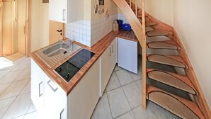 Keittiössä on sisäänrakennettu liesi, pesuallas ja pieni jääkaappi. Puinen portaikko johtaa ylemmälle tasolle.