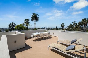 Enjoy breathtaking city views from this rooftop terrace, featuring a table, chairs, and comfortable lounge seating.